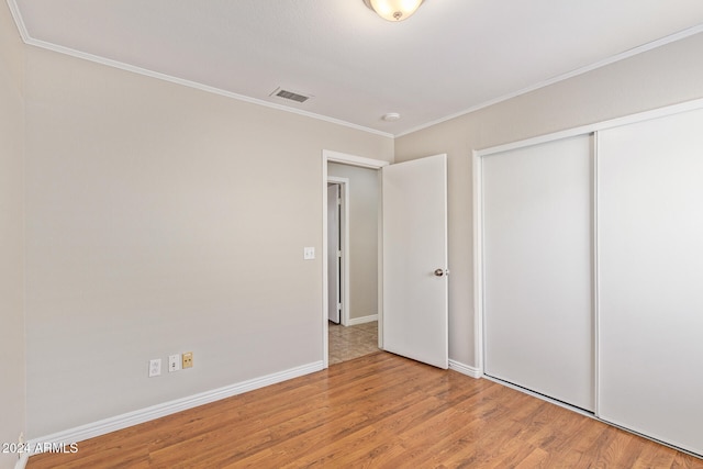 unfurnished bedroom featuring a closet, crown molding, and light hardwood / wood-style floors