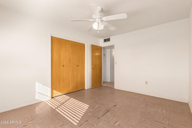 unfurnished bedroom with ceiling fan, light parquet floors, and a closet