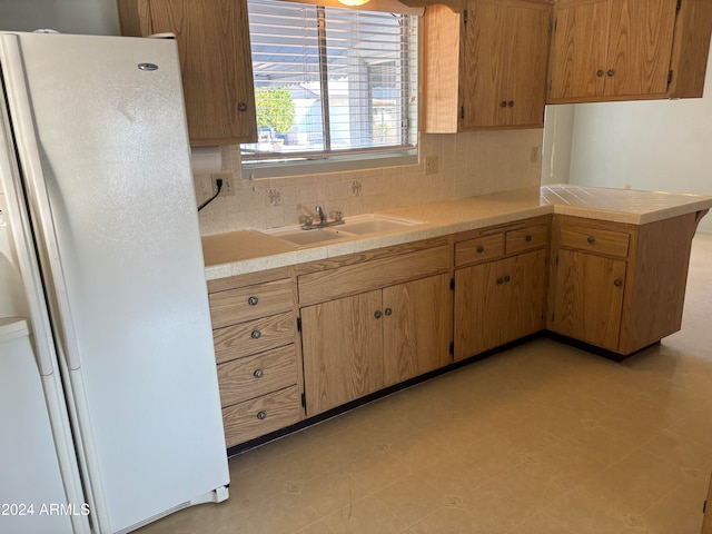 kitchen featuring white fridge, sink, and backsplash