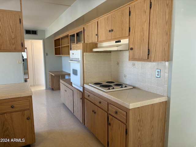 kitchen with decorative backsplash, light tile patterned flooring, and white appliances