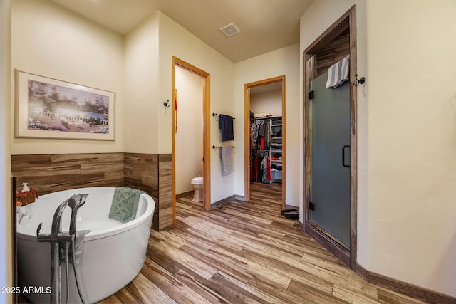 2352 Immelman Cir, Overgaard, AZ 85933 - bathroom with a soaking tub, a walk in closet, a stall shower, wood finished floors, and toilet