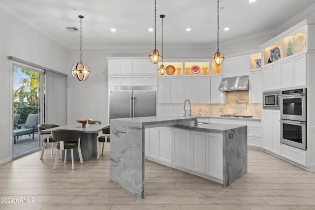 kitchen with white cabinets, an island with sink, extractor fan, and hanging light fixtures