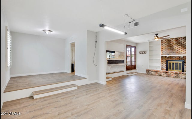 unfurnished living room with ceiling fan, light hardwood / wood-style flooring, and a brick fireplace