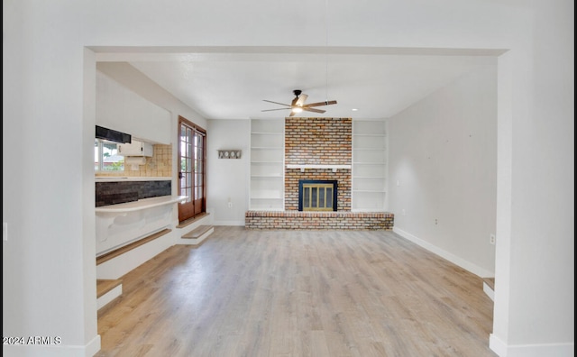 unfurnished living room with a fireplace, light wood-type flooring, built in features, and ceiling fan