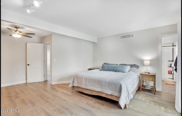 bedroom featuring a barn door, light hardwood / wood-style floors, and ceiling fan