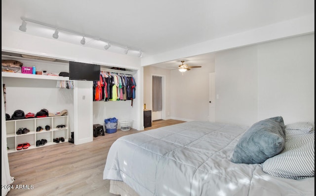 bedroom featuring ceiling fan, a closet, rail lighting, and wood-type flooring