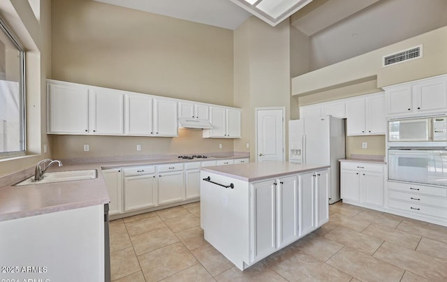 6923 W Laredo St, Chandler, AZ 85226 - kitchen with white appliances, high vaulted ceiling, under cabinet range hood, light countertops, and a center island