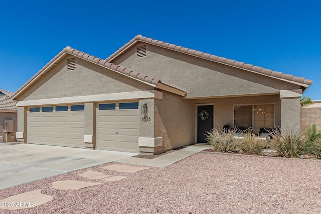 view of front of home with stucco siding, a garage, driveway, and a tiled roof