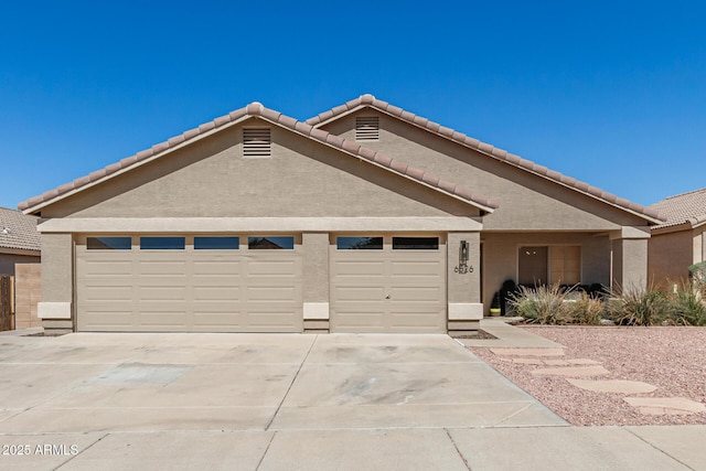 ranch-style house with stucco siding, a garage, and concrete driveway