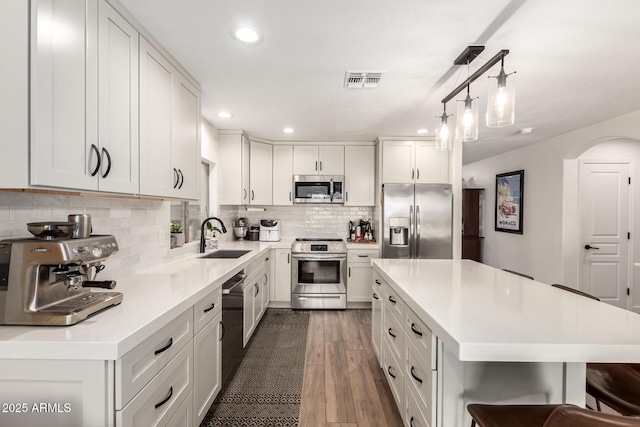 kitchen with visible vents, backsplash, light countertops, stainless steel appliances, and a sink