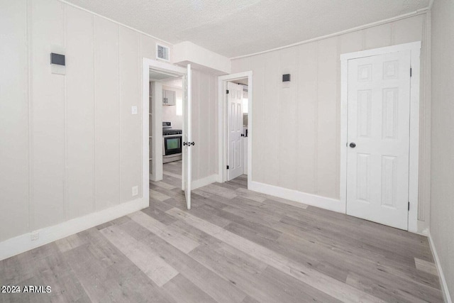 spare room with a textured ceiling and light hardwood / wood-style floors