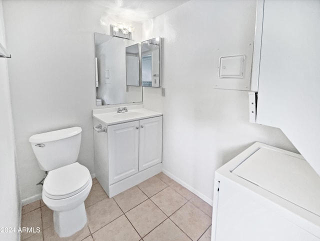 bathroom featuring baseboards, toilet, vanity, tile patterned floors, and washer / clothes dryer