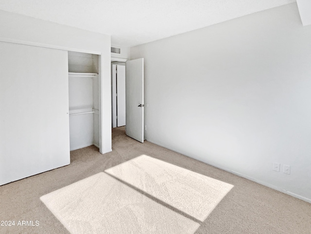 unfurnished bedroom with a closet, visible vents, and carpet