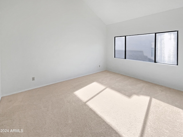 spare room with carpet flooring and vaulted ceiling