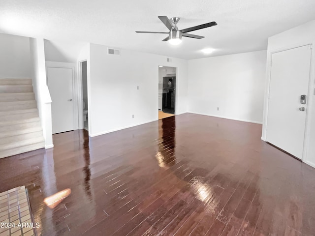 unfurnished living room with visible vents, stairs, ceiling fan, and wood finished floors