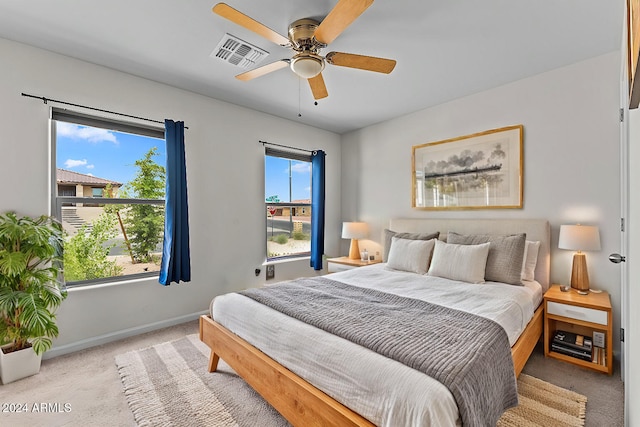 bedroom with multiple windows, light colored carpet, and ceiling fan