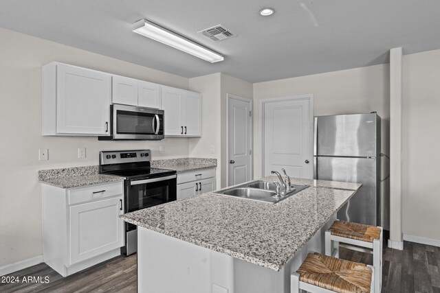 kitchen with sink, a breakfast bar area, dark hardwood / wood-style flooring, white cabinetry, and stainless steel appliances