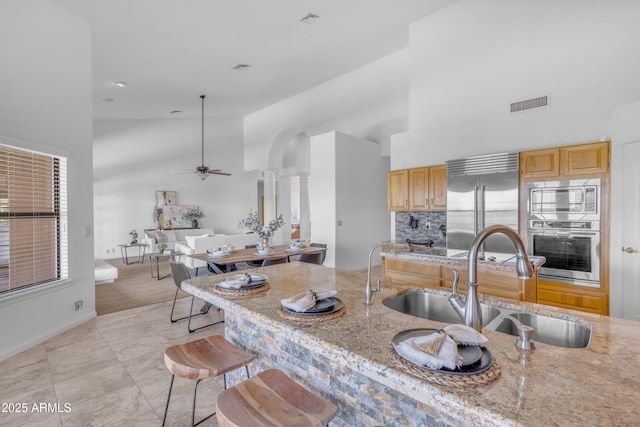 12605 E Kalil Dr, Scottsdale, AZ 85259 - kitchen with built in appliances, high vaulted ceiling, ceiling fan, light stone counters, and ornate columns