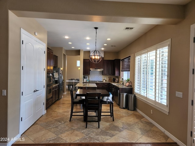 kitchen featuring decorative backsplash, dark brown cabinetry, decorative light fixtures, and a kitchen island