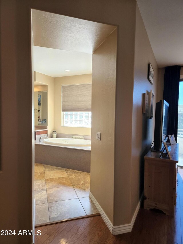 hall with a textured ceiling and light hardwood / wood-style floors