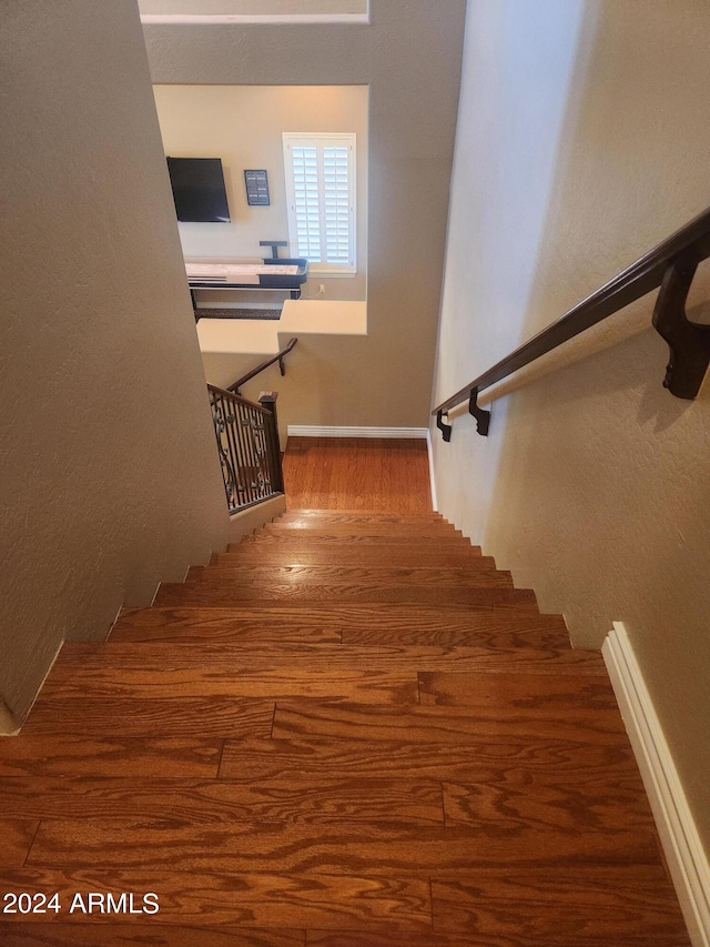 staircase featuring baseboard heating and wood-type flooring