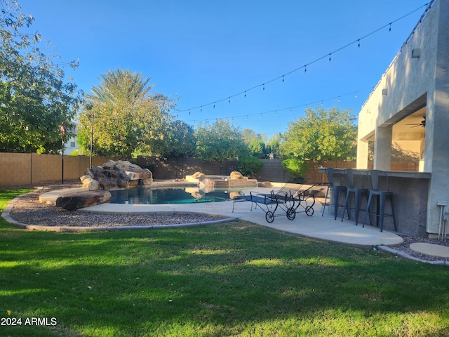 view of yard featuring a patio area, a fenced in pool, and a bar