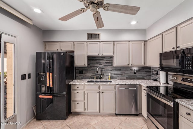 kitchen featuring light stone counters, sink, tasteful backsplash, and black appliances