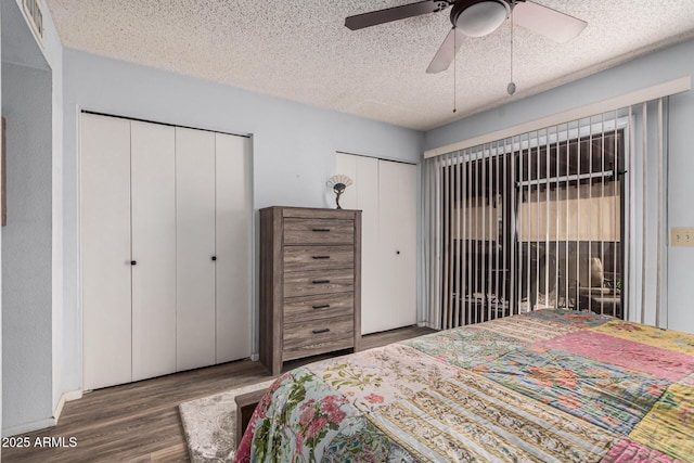 bedroom featuring multiple closets, ceiling fan, dark wood-type flooring, and a textured ceiling