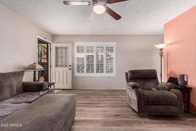 living room featuring hardwood / wood-style flooring, ceiling fan, and a textured ceiling