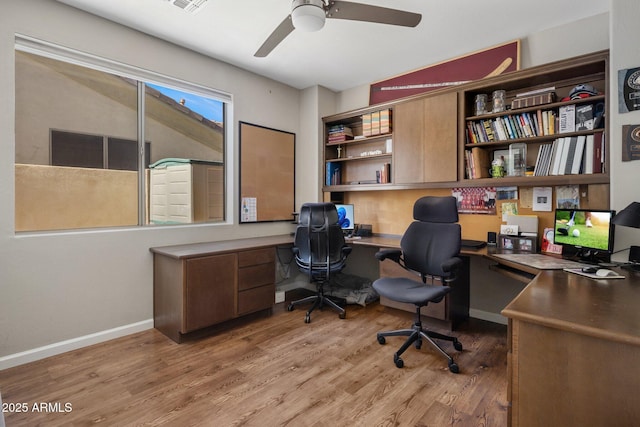 office featuring baseboards, light wood-style floors, a ceiling fan, and built in study area