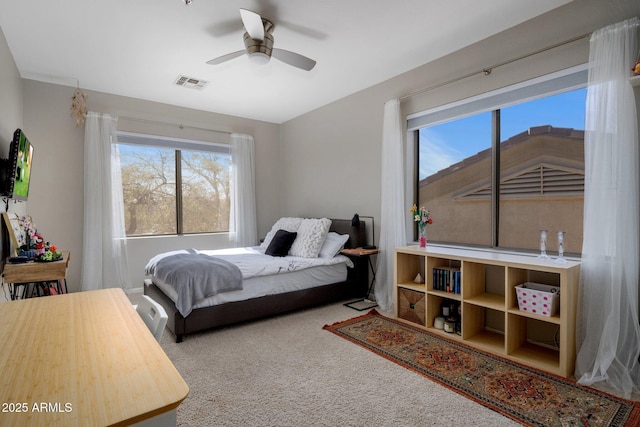 carpeted bedroom with visible vents, multiple windows, and ceiling fan