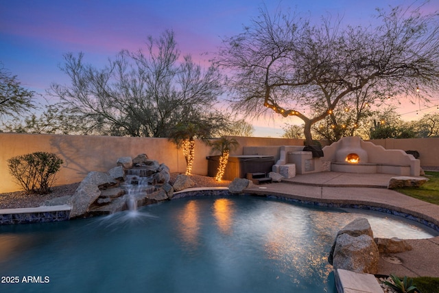 pool at dusk featuring a patio, a fenced backyard, and a hot tub