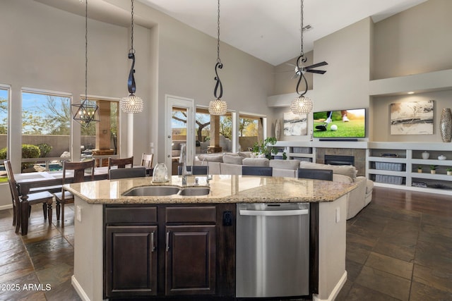 kitchen with a kitchen island with sink, a sink, a tile fireplace, dishwasher, and open floor plan