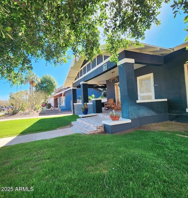 back of house with a lawn and stucco siding