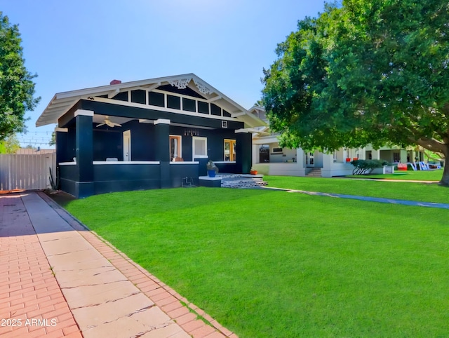 view of front of house featuring a ceiling fan, a front yard, and fence