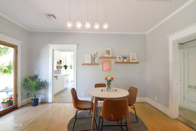 dining area with crown molding, light wood-style floors, and visible vents