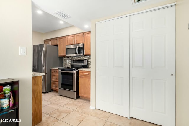 kitchen featuring light tile patterned flooring, stainless steel appliances, visible vents, tasteful backsplash, and brown cabinetry