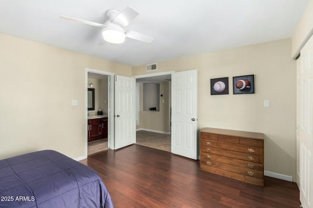 bedroom with baseboards, visible vents, dark wood finished floors, ceiling fan, and ensuite bathroom