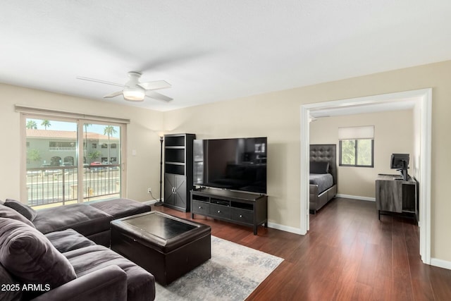 living area with a healthy amount of sunlight, baseboards, dark wood finished floors, and a ceiling fan