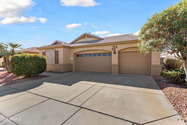 view of front facade with concrete driveway, an attached garage, a tile roof, and stucco siding