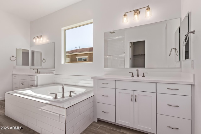 20274 W Monterey Way, Buckeye, AZ 85396 - bathroom with a garden tub, two vanities, wood finished floors, and a shower