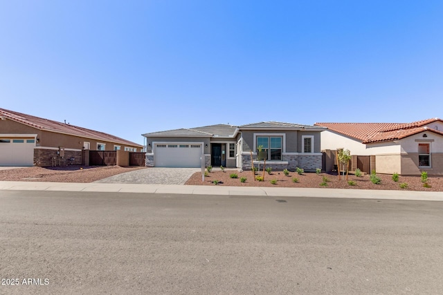 20274 W Monterey Way, Buckeye, AZ 85396 - view of front of house with stone siding, driveway, an attached garage, stucco siding, and a tile roof