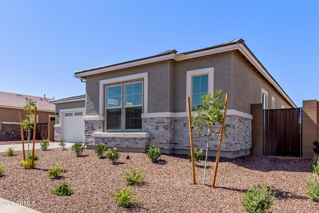 20274 W Monterey Way, Buckeye, AZ 85396 - view of front of house featuring stone siding, an attached garage, stucco siding, and a gate