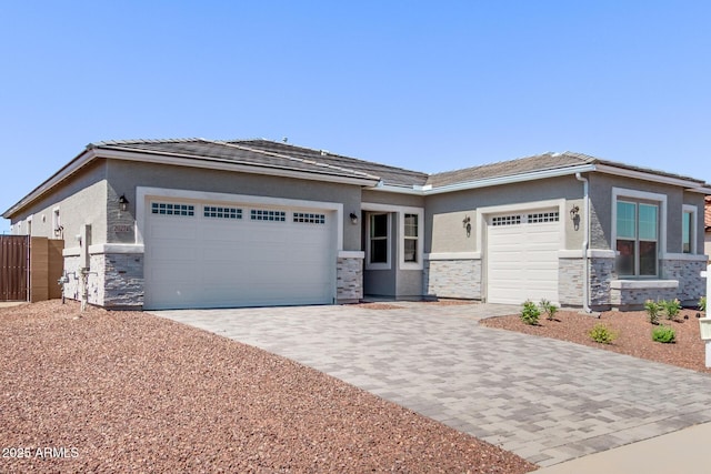 20274 W Monterey Way, Buckeye, AZ 85396 - view of front of home featuring an attached garage, stone siding, decorative driveway, and stucco siding