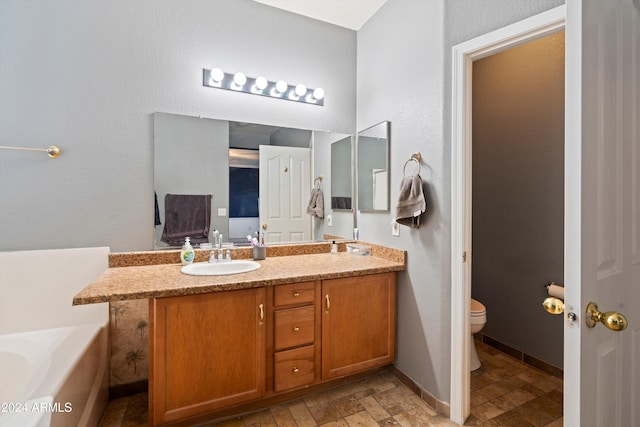 bathroom with a bath, vanity, and toilet