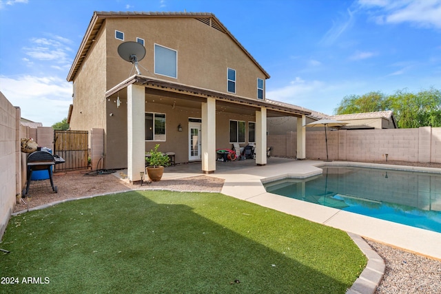 rear view of property with a patio, a fenced in pool, and a yard