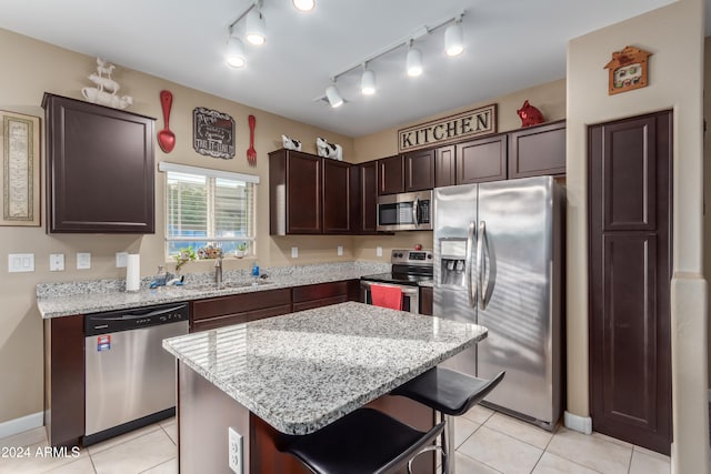 kitchen featuring dark brown cabinets, rail lighting, a breakfast bar, stainless steel appliances, and a center island