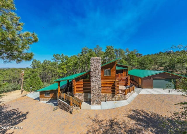 log home with a chimney, an outbuilding, and metal roof