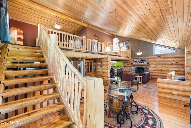 stairs with wood ceiling, rustic walls, a fireplace, wood finished floors, and high vaulted ceiling