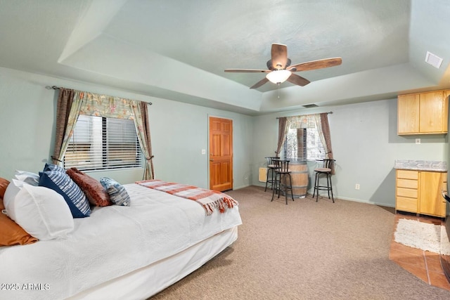 bedroom featuring a raised ceiling, baseboards, visible vents, and light carpet